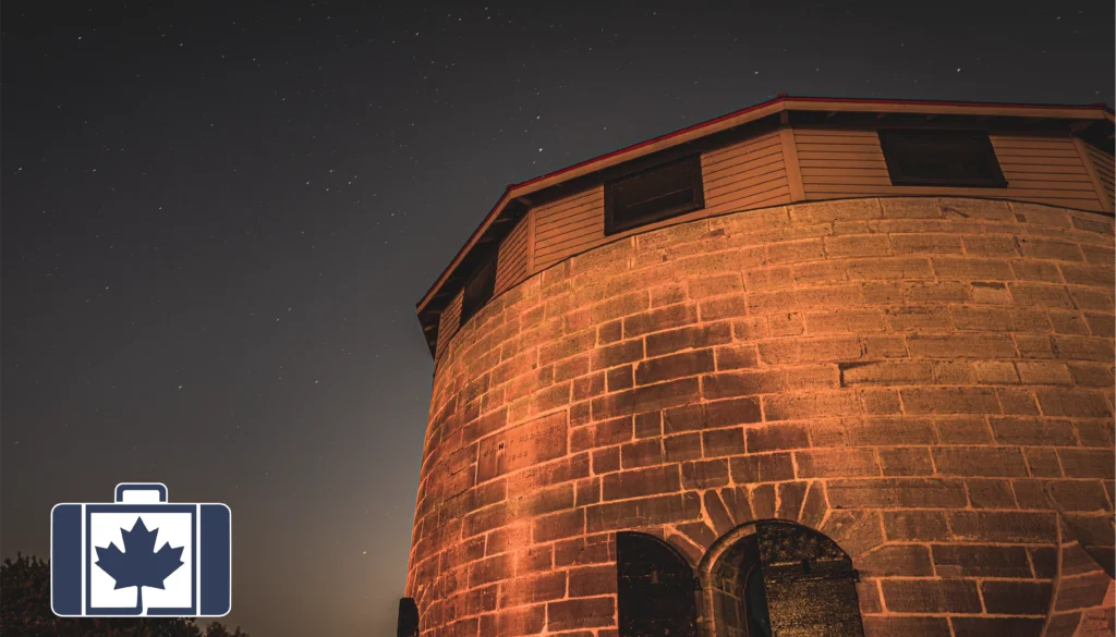 Accessing Medical Care in Canada: A Visitors Guide A historic stone Martello tower in Kingston, Ontario, illuminated against a starry night sky.