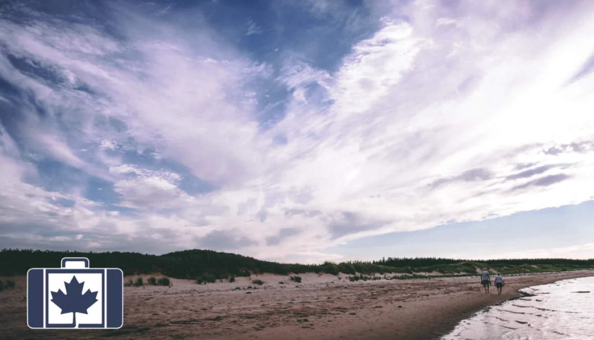 A couple walking on a beach under a partly cloudy sky in Prince Prince Edward Island