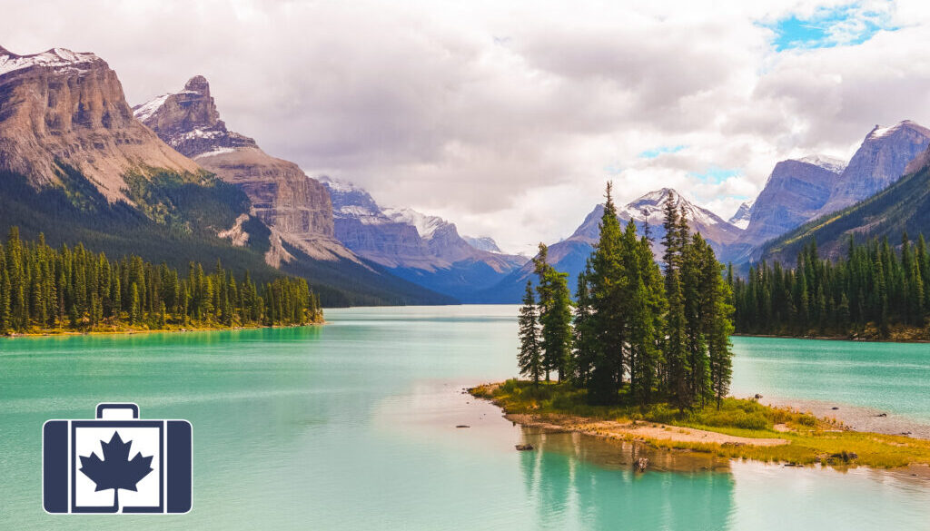 VisitorsInsurance.ca Spirit Island, a small grove of trees, sits in the turquoise waters of Maligne Lake with the snow-capped Canadian Rockies in the background.