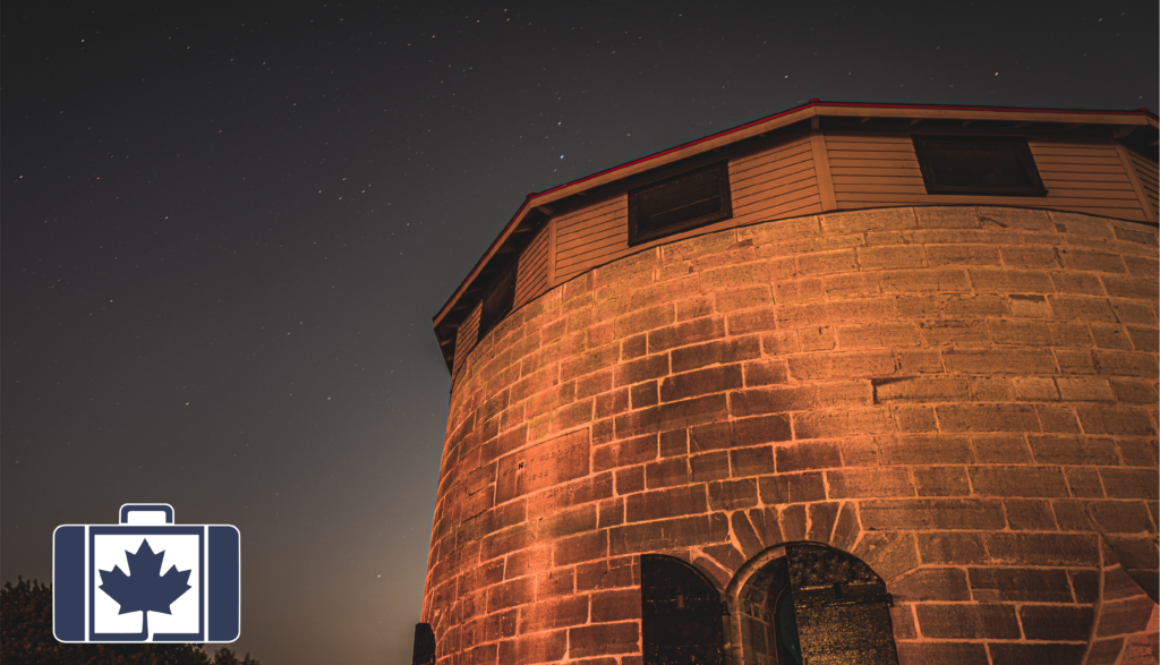 A historic stone Martello tower in Kingston, Ontario, illuminated against a starry night sky.